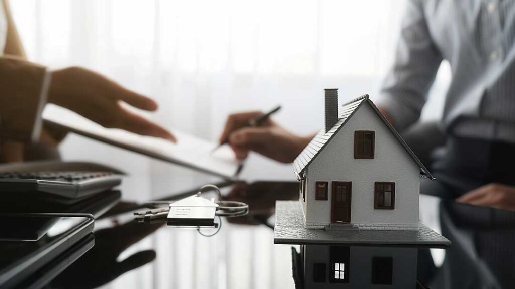 An insurance adjuster reviews accident photos and claim documents with a homeowner at a kitchen table.